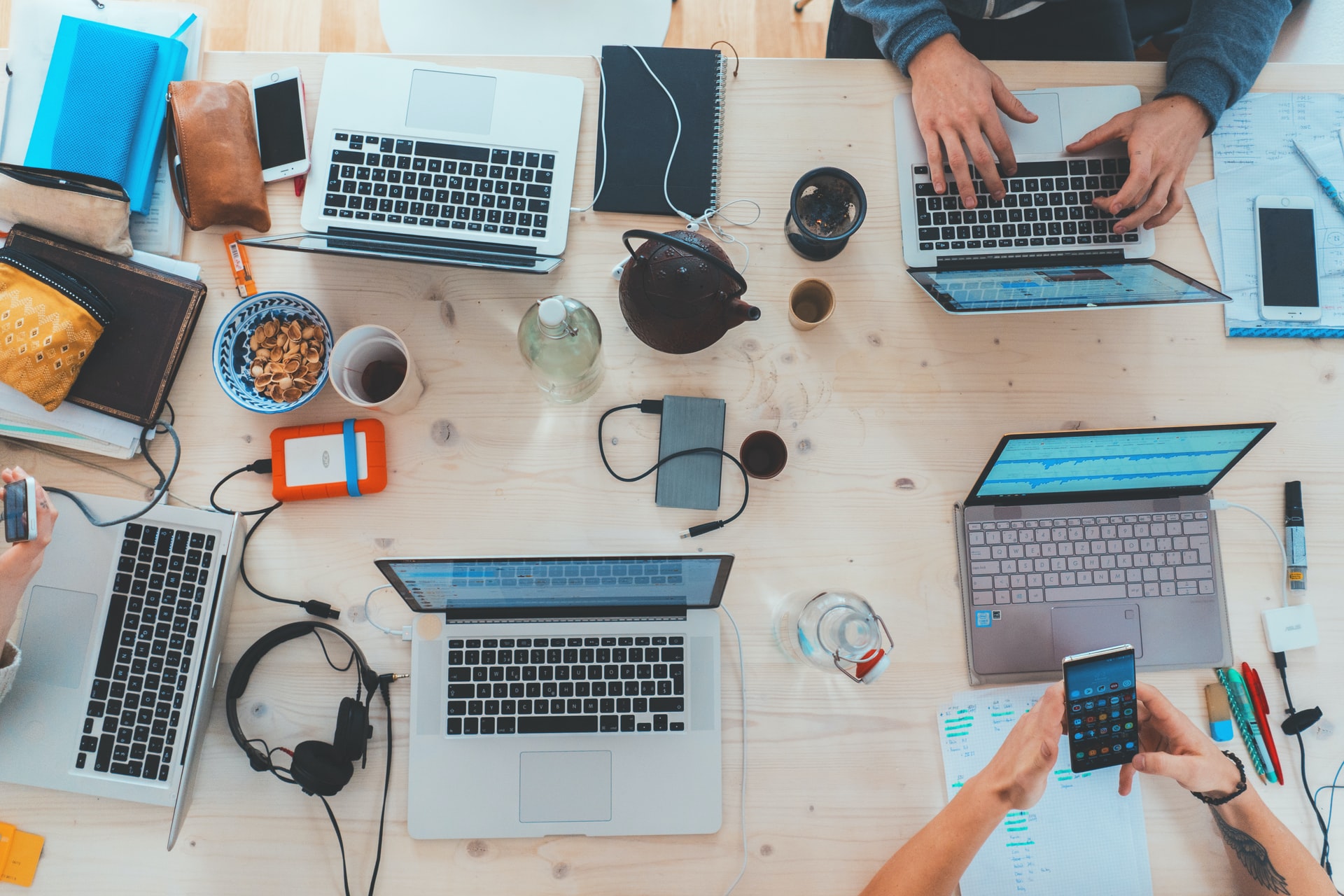 people sitting down at table with assorted laptops and electronic gear